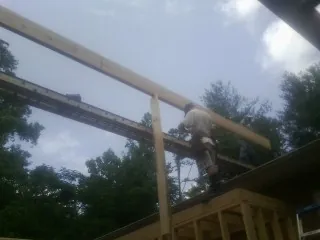 Carpenter setting a ridge beam over a new addition frame — Ice Dam Removal by Roofing Brothers in Elm City