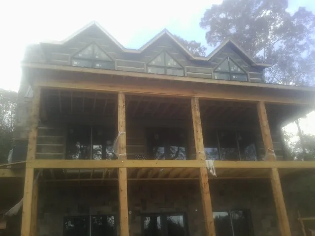 Dormers and porch framing on a large log home under construction — Roof Coating work by our crew in Elm City