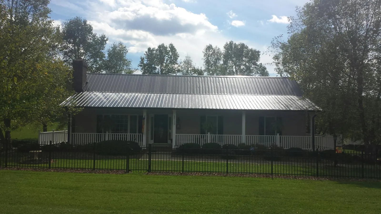 Gray metal roof on a brick ranch with a full width front porch — Gutter Guard Installation work by our crew in Elm City