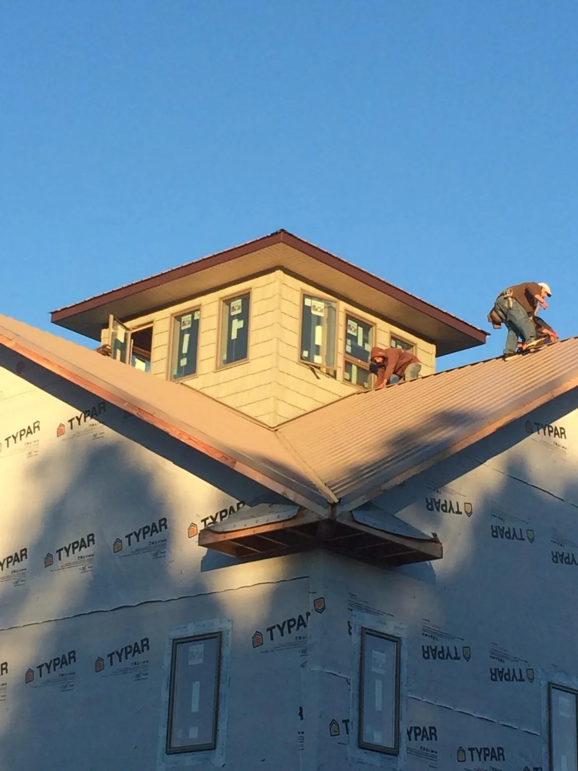 Roofers working around a rooftop cupola on a new metal roof at sunset — Roof Waterproofing in Elm City by Roofing Brothers